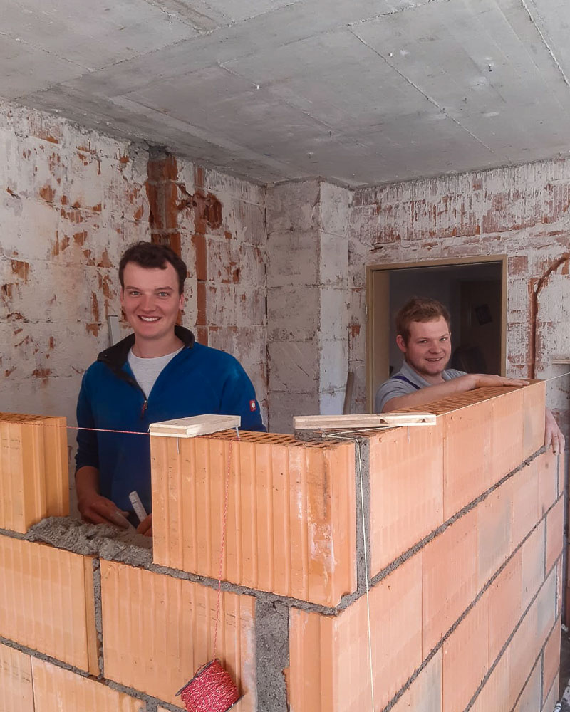 Geschäftsführer Florian Lindmair mit seinem Mitarbeiter hinter einer gemauerten Wand